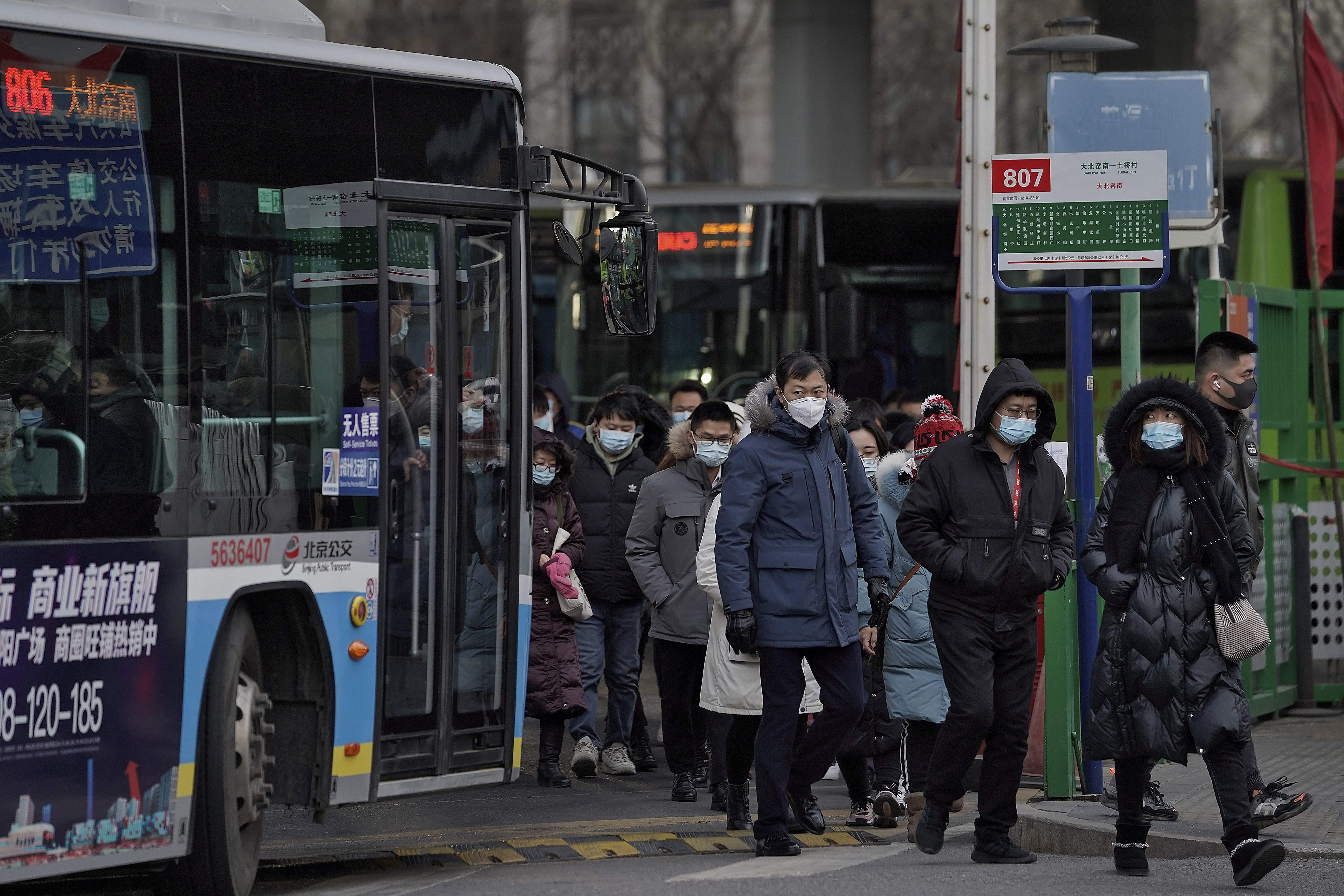 People wearing face masks to help curb the spread of the coronavirus walk out from a bus station for the traveller from the outskirts of Beijing on Monday, Jan. 11, 2012. Chinese health authorities say scores more people have tested positive for coronavirus in Hebei province bordering on the capital Beijing. The outbreak focused on the Hebei cities of Shijiazhuang and Xingtai is one of China's most serious in recent months and comes amid measures to curb the further spread during next month's Lunar New Year holiday. (AP Photo/Andy Wong)