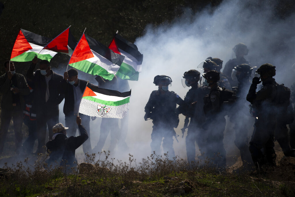 FILE - In this Thursday, Dec. 3, 2020. file photo, Israeli border police officers and Palestinians clash during a protest against the expansion of Israeli Jewish settlements near the West Bank town of Salfit. Israel's premier human rights group has begun describing both Israel and its control of the Palestinian territories as a single 