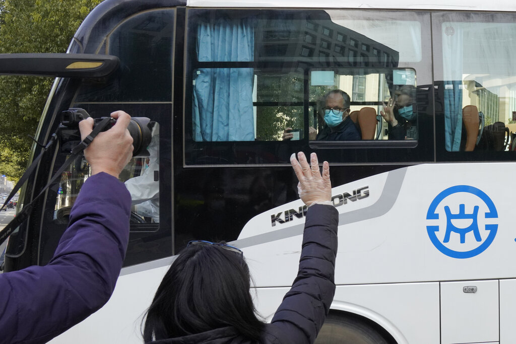 Workers wave off a team of experts from the World Health Organization who ended their quarantine and left the quarantine hotel in a bus in Wuhan in central China's Hubei province on Thursday, Jan. 28, 2021. The WHO team emerged from quarantine to start field work in a fact-finding mission on the origins of the virus that caused the COVID-19 pandemic. (AP Photo/Ng Han Guan)
