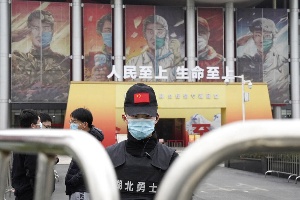 A security officer wearing a mask and a cap with the Chinese national flag guards the entrance after the World Health Organization team arrive at an exhibition about the fight against the coronavirus in Wuhan in central China's Hubei province on Saturday, Jan. 30, 2021. The World Health Organization team investigating the origins of the coronavirus pandemic visited another Wuhan hospital that had treated early COVID-19 patients on their second full day of work on Saturday. (AP Photo/Ng Han Guan)