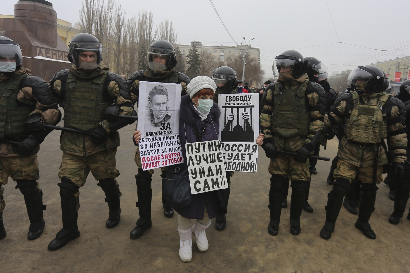A woman holds posters as police stand blocking approaches to the square,  during a protest against the jailing of opposition leader Alexei Navalny in Volgograd, Russia, Sunday, Jan. 31, 2021. Posters, left to right, read: "Today they have come after Navalny, tomorrow they will come after me, the day after tomorrow they will come after you", "Putin, you better go away yourself", "Russia will be free". Thousands of people have taken to the streets across Russia to demand the release of jailed opposition leader Alexei Navalny, keeping up the wave of nationwide protests that have rattled the Kremlin. Hundreds have been detained by police. (AP Photo/Dmitry Rogulin)