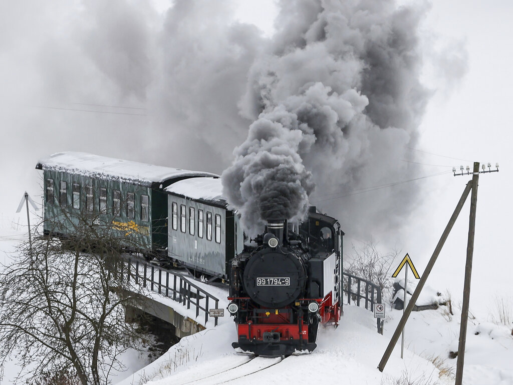 The Fichtelbergbahn steams through the snow-covered Ore Mountains near Sehmatal, Germany, Tuesday, Jan.19, 2021. Passengers are currently offered a wonderful view of the snow-covered landscape. But the trains are only sparsely occupied, just like those of the other Bimmelbahnen in Saxony. Due to the Corona restrictions, the trains, which are mainly used by tourists, do not exceed 25 percent capacity at the moment. (Jan Woitas/dpa via AP)