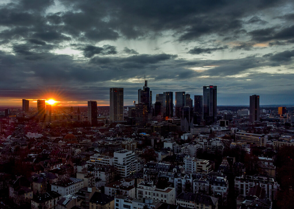 The sun rises between clouds behind the buildings of the banking district in Frankfurt, Germany, Thursday, Jan. 21, 2021. (AP Photo/Michael Probst)