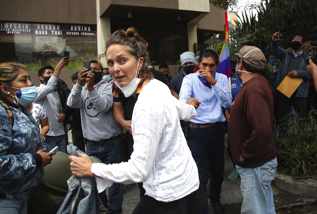 Manuela Picq holds the hand of her husband,  Indigenous rights and environmentalist activist Yaku Perez, who is running for president with the Pachakutik political party, as they move through supporters outside the Swissotel where international observers of the previous day's presidential elections are staying in Quito, Ecuador, Monday, Feb. 8, 2021. Perez's party is demanding observers be vigilant of the vote count while it is still undecided who will make it to the second-round vote in April, him or his rival, a conservative former banker Guillermo Lasso, to run against young leftist Andrés Arauz. (AP Photo/Dolores Ochoa)