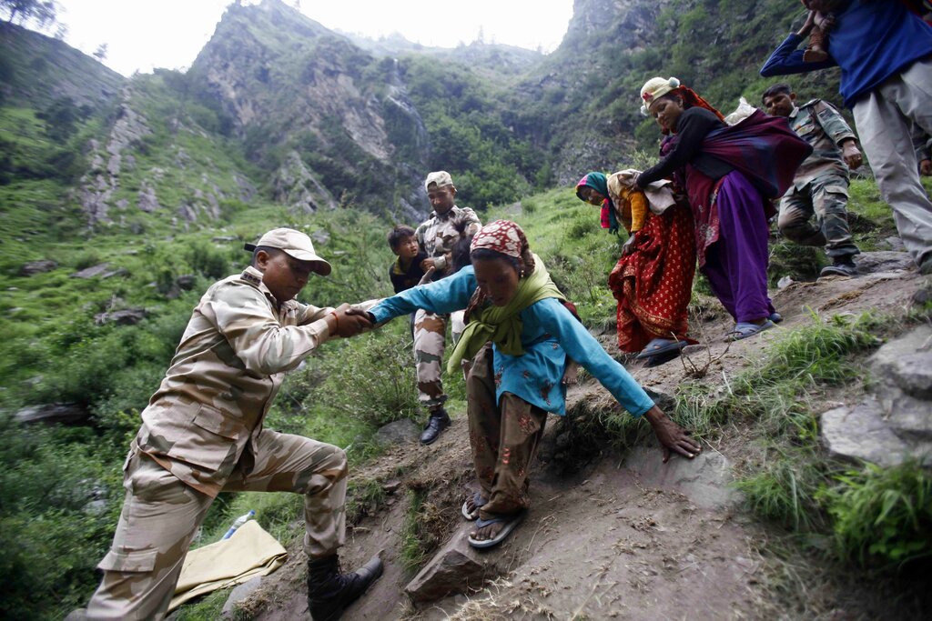 FILE- In this June 23, 2013 file photo, Indian army soldiers help people stranded due to monsoon flooding and landslides climb down a mountain in Govindghat, India. The ecologically sensitive Himalayan region is prone to flash floods and landslides. More than 6,000 people are believed to have been killed in floods in 2013 which were triggered by the heaviest monsoon rains in decades. (AP Photo/Rafiq Maqbool, File)