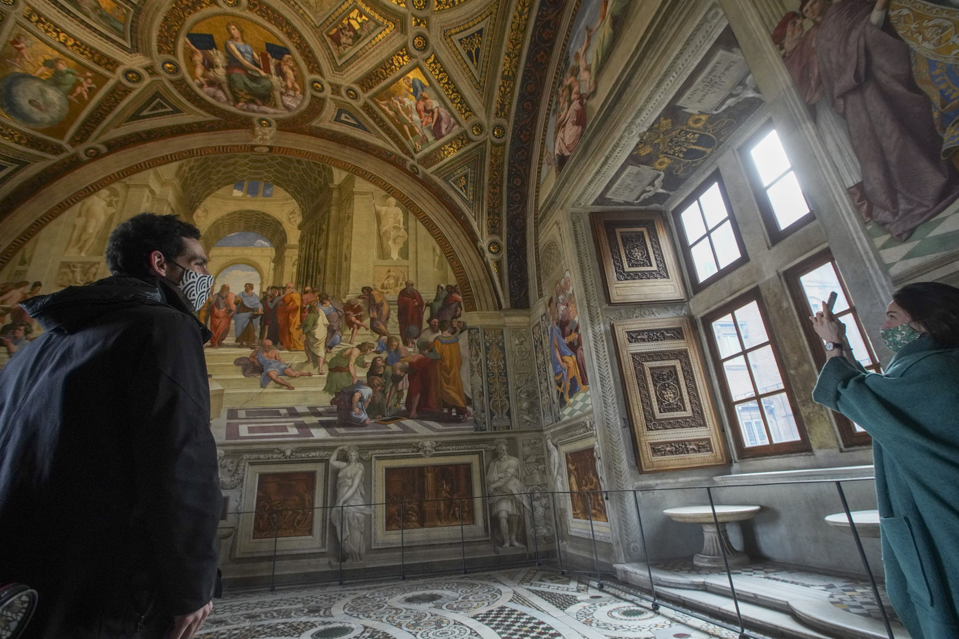 Visitors Julia Lammer from Austria, right, and Nico Epstein from Canada admire the frescoes of one the Raphael rooms at the Vatican Museums Monday, Feb. 1, 2021. The Vatican Museums reopened Monday to visitors after 88 days of shutdown following COVID-19 containment measures. (AP Photo/Andrew Medichini)
