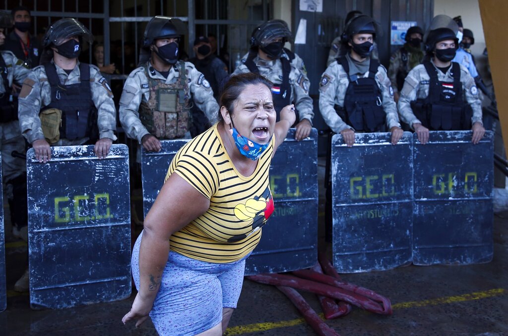 A relative protests against the police as she pleads for the life of her husband, an inmate at the Tacumbu prison, after the inmates rioted and took control of the place in Asuncion, Paraguay, Tuesday, Feb. 16, 2021. (AP Photo/Jorge Saenz)