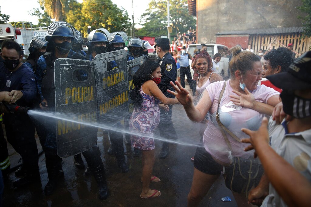 Relatives of inmates are sprayed with a firehose as they protest outside Tacumbu prison after the inmates rioted and took control of the place in Asuncion, Paraguay, Tuesday, Feb. 16, 2021. (AP Photo/Jorge Saenz)