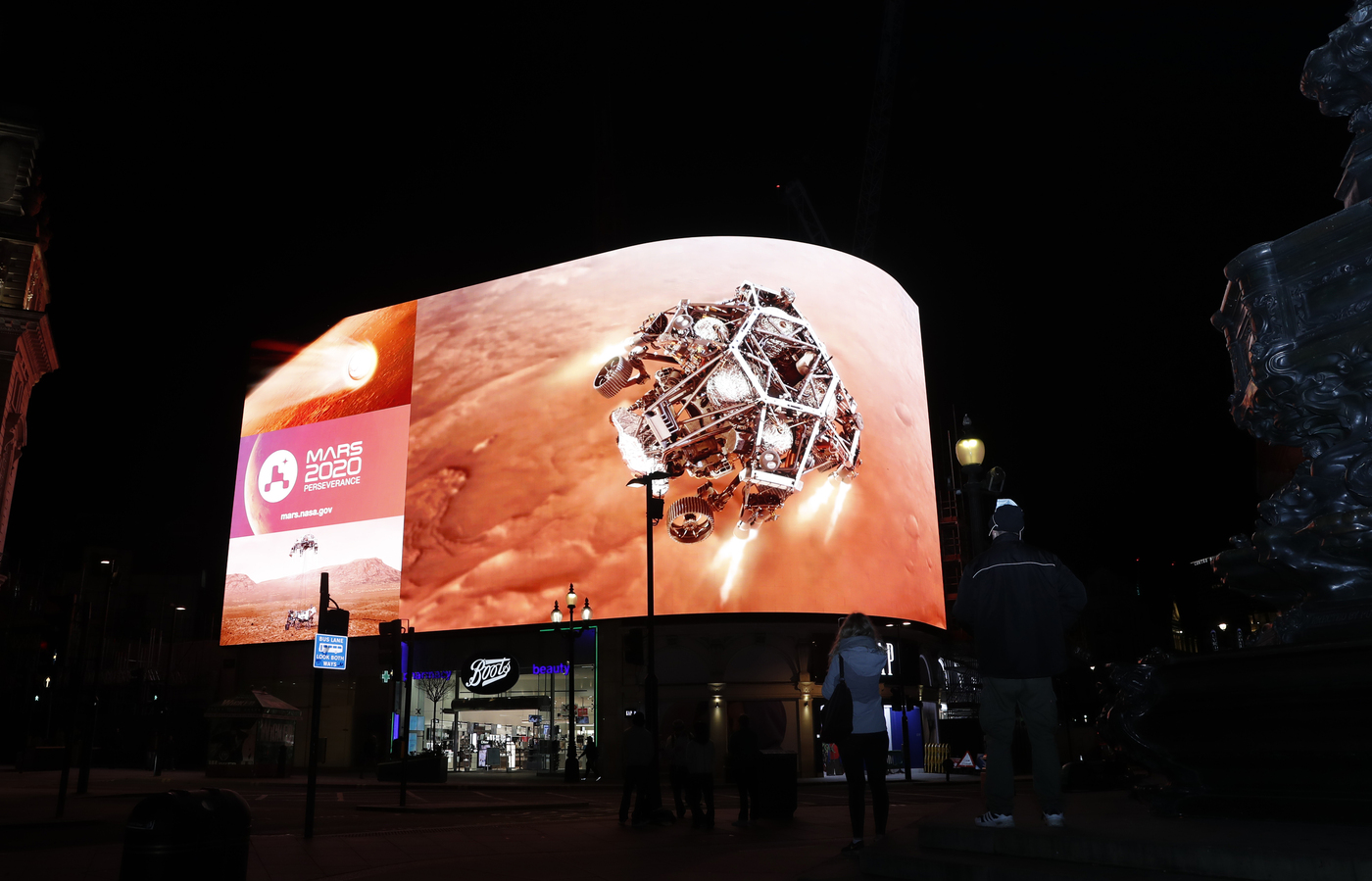 Images from Nasa are streamed live showing the landing of NASA's Perseverance on Mars, shown on Piccadilly Lights in central London, Thursday Feb. 18, 2021. The Mars rover landing mission begins it's search for traces of life after the successful landing, to explore and collect samples for future return to Earth.(AP Photo/Alastair Grant)
