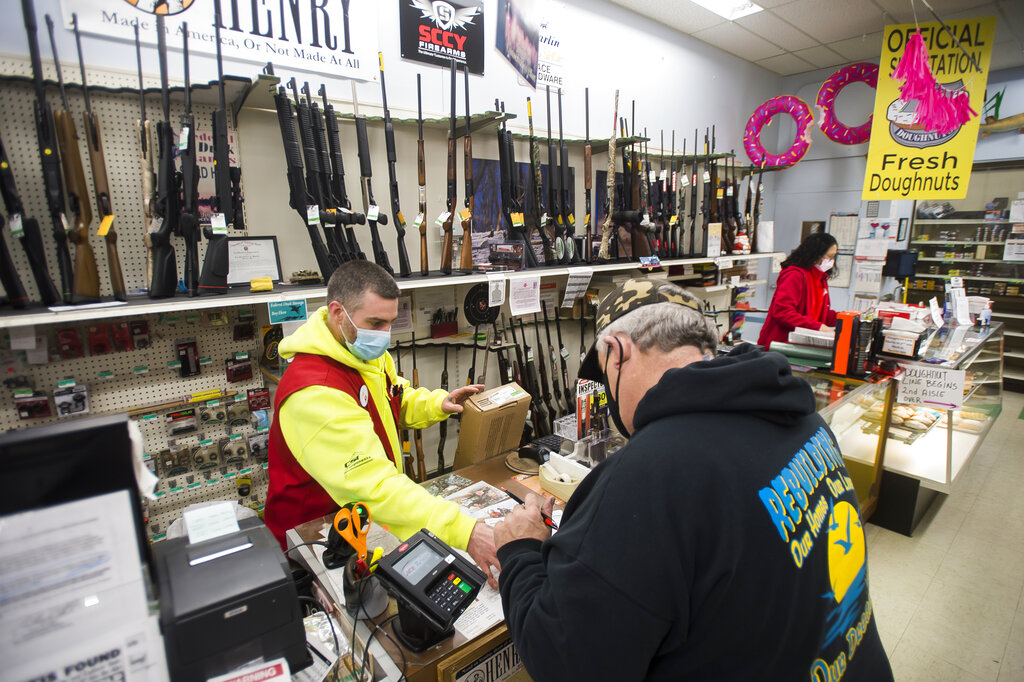 Midland Ace Hardware manager of sporting goods Jon Leiner, left, assists Virgil Millhisler of Hope, right, in purchasing a rifle, Thursday, Feb. 11, 2021 at the store in Midland, Mich.. (Katy Kildee/Midland Daily News via AP)