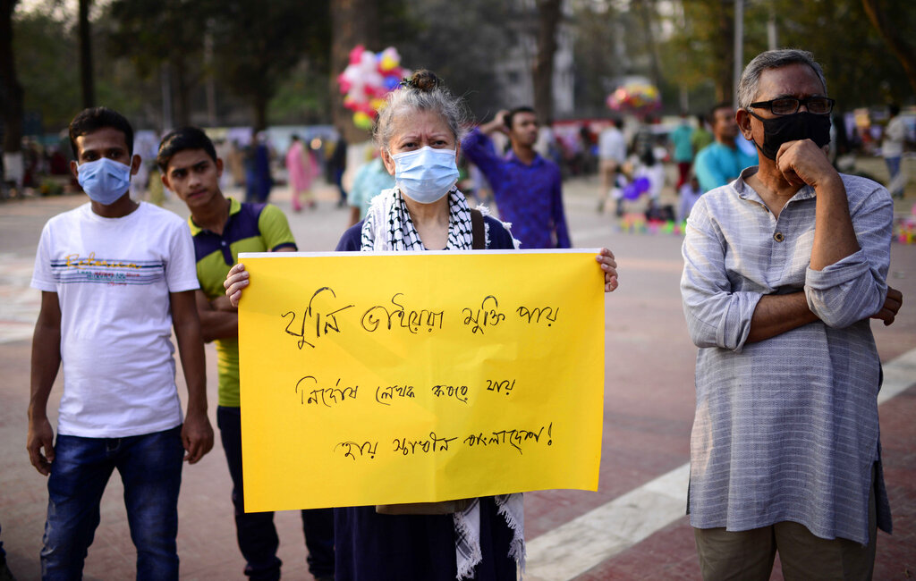 A woman holds a placard to protest the death in prison of a writer who was arrested on charges of violating the sweeping digital security, in Dhaka, Bangladesh, Friday, Feb. 26, 2021. Mushtaq Ahmed, 53, was arrested in Dhaka in May last year for making comments on social media that criticized the Prime Minister Sheikh Hasina government's handling of the coronavirus pandemic. He had been denied bail at least six times. Placrad reads 