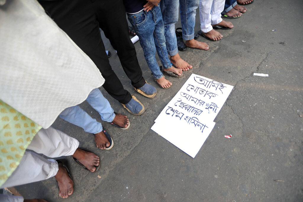 Protesters offer Friday prayers during a demonstration against the death in prison of a writer who was arrested on charges of violating the sweeping digital security, in Dhaka, Bangladesh, Friday, Feb. 26, 2021. Mushtaq Ahmed, 53, was arrested in Dhaka in May last year for making comments on social media that criticized the Prime Minister Sheikh Hasina government's handling of the coronavirus pandemic. He had been denied bail at least six times. The poster reads 