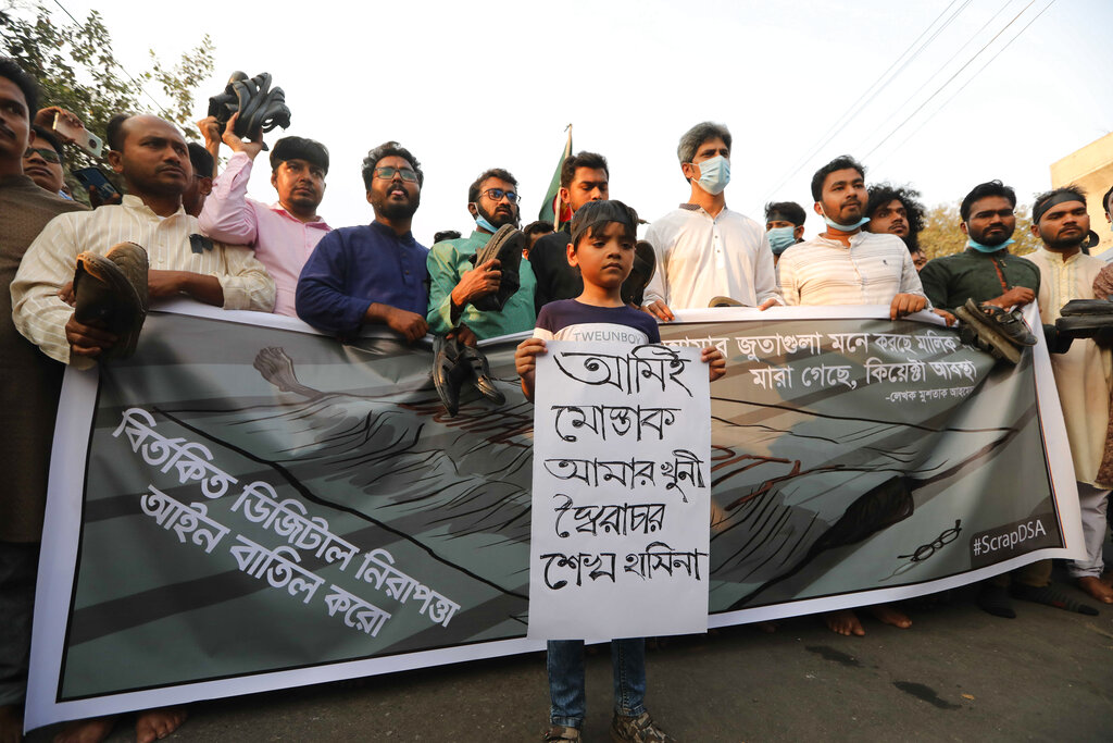 A boy joins adults during a demonstration against the death in prison of a writer who was arrested on charges of violating the sweeping digital security, in Dhaka, Bangladesh, Friday, Feb. 26, 2021. Mushtaq Ahmed, 53, was arrested in Dhaka in May last year for making comments on social media that criticized the Prime Minister Sheikh Hasina government's handling of the coronavirus pandemic. He had been denied bail at least six times. The poster reads 