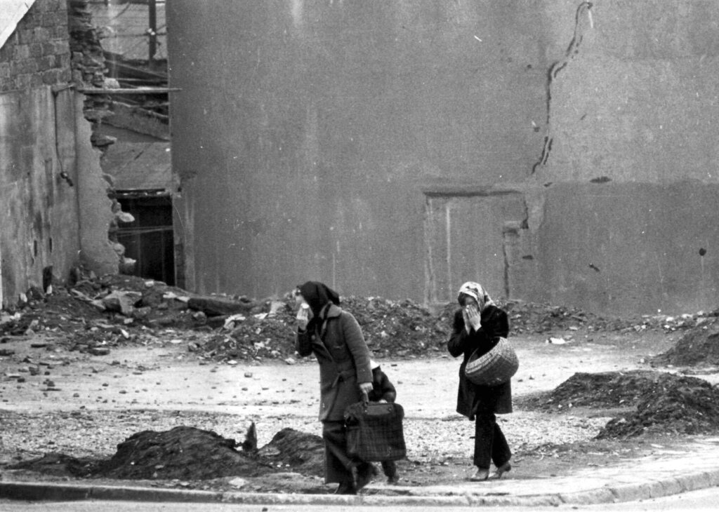 Two women cover their faces with handkerchiefs to protect themselves against teargas fired by British police against rioting youth in Londonderry, Northireland on Febr. 20, 1972. (AP Photo) --- Zwei Frauen schuetzen sich am 20. Februar 1972 in Londonderry mit Taschentuechern vor dem Traenengas, das die britische Polizei gegen steinewerfende Jugendliche eingesetzt hat. Weniger als einen Monat  zuvor, am 30. Januar 1972, toeteten britische Soldaten in Derry 14 unbewaffnete Katholiken. Jener Tag ist als 'Bloody Sunday' in die Geschichte eingegangen. Nach einem fast drei Jahrzehnte dauernden Konflikt, in dem mehr als 3200 Menschen starben, haben sich die Protestanten und Katholiken Nordirlands am Freitag, 10. April 1998, auf ein Friedensabkommen geeinigt.  (AP Photo/Michel Laurent)