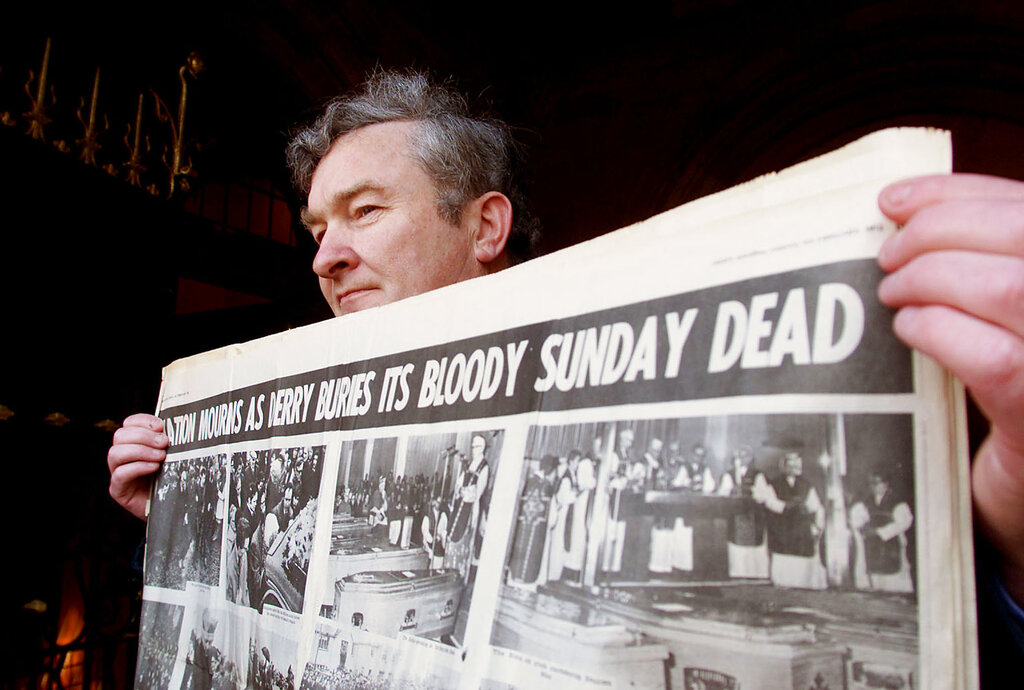 John Hanley holds a copy of the Derry Journal from 1972, during The opening day of the Bloody Sunday Inquiry in the Guild Hall in Londonderry, Northern Ireland, Monday, March 27, 2000. The inquiry will investigate the shooting in 1972 when the British Army shot dead fourteen Catholics. (AP Photo/Peter Morrison)