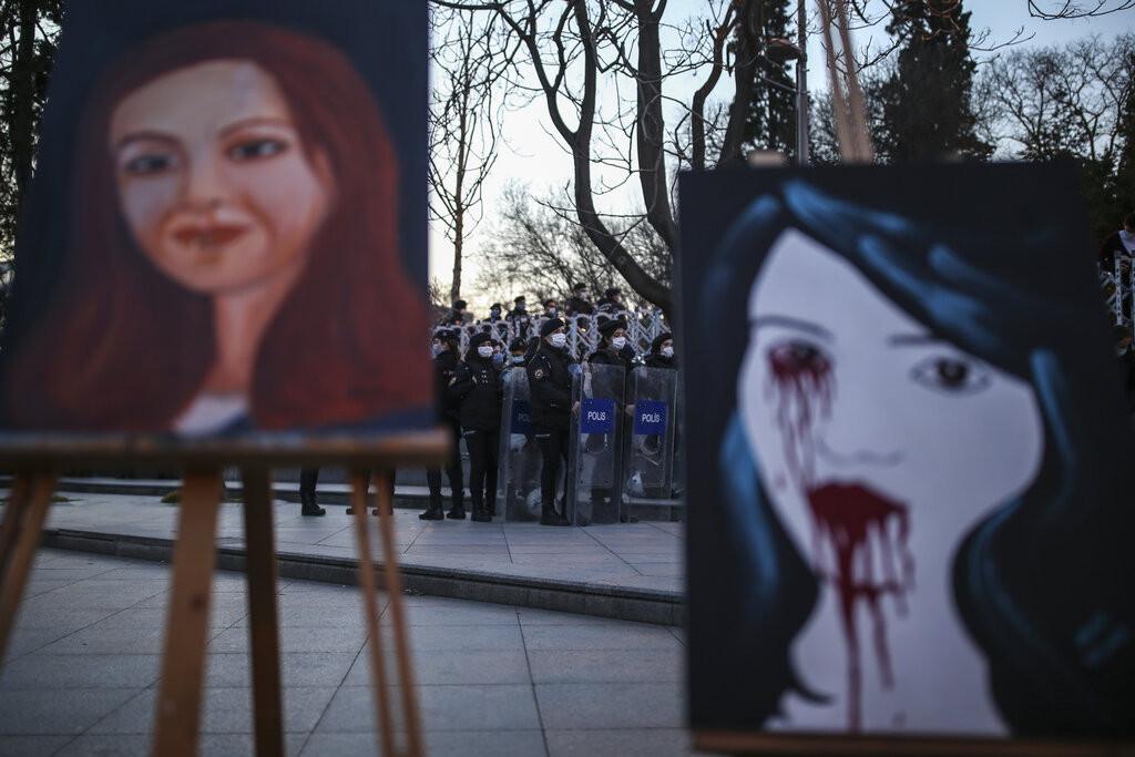 Turkish riot police officers keep a watchful eye as protesters' paintings are seen during a rally to denounce violence against women ahead of International Women's Day, in Istanbul, Friday, March 6, 2021. (AP Photo/Emrah Gurel)