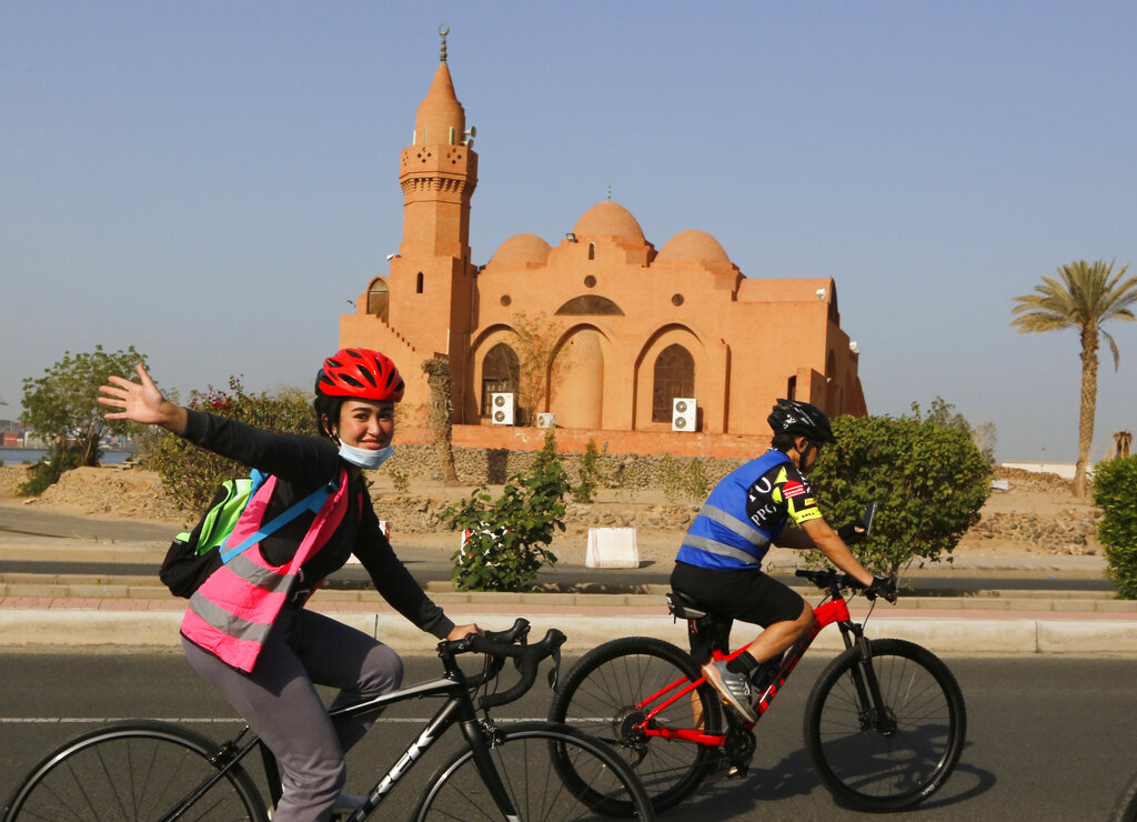 Saudi cyclist Maya Jambi, reacts as she rides her bicycle past the Corniche Mosque in Jiddah, Saudi Arabia, Saturday, March 6, 2021. The brave cyclist team, which was formed in 2019 aiming to normalize the sport for women, organize a tour cycling ahead of International Women's Day. (AP Photo/Amr Nabil)