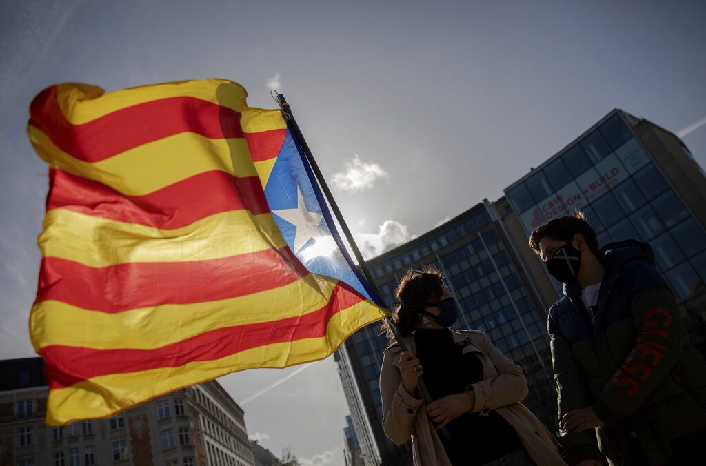 A demonstrator waves the flag of Catalonia as she takes part in a protest condemning the arrest of rap artist Pablo Hasel in Brussels, Tuesday, Feb. 23, 2021. The imprisonment of rap artist Pablo Hasel, for his music and tweets praising terrorist violence and insulting the Spanish monarchy, has set off a powder keg of pent-up rage this week in Spain. (AP Photo/Virginia Mayo)