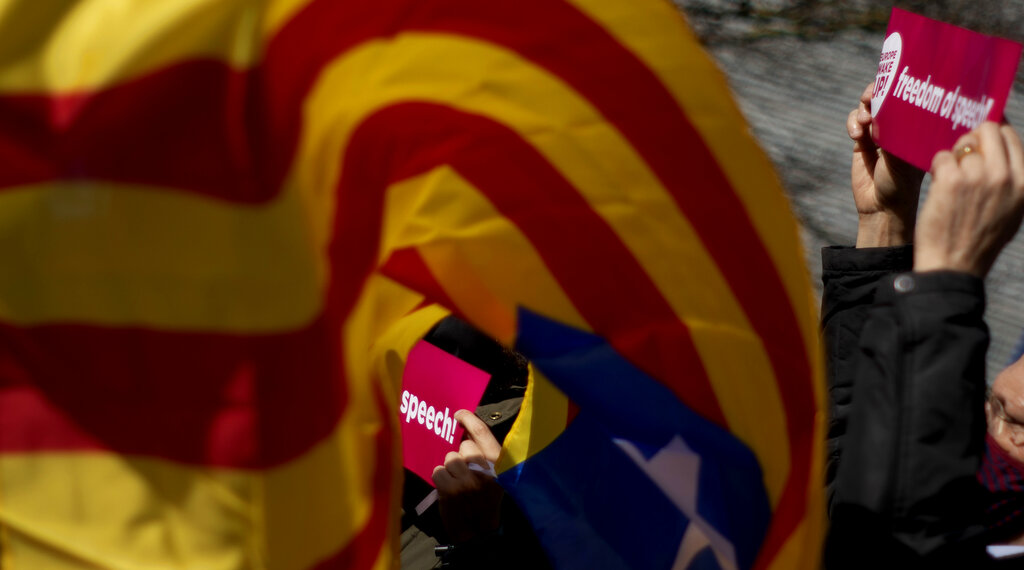 Demonstrators wave banners and the flag of Catalonia as they take part in a protest condemning the arrest of rap artist Pablo Hasel in Brussels, Tuesday, Feb. 23, 2021. The imprisonment of rap artist Pablo Hasel, for his music and tweets praising terrorist violence and insulting the Spanish monarchy, has set off a powder keg of pent-up rage this week in Spain. (AP Photo/Virginia Mayo)
