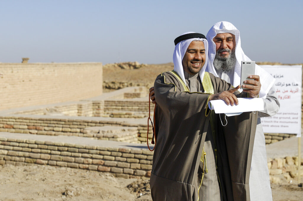 People take selfies next to what is believed to be the house of Abraham near the Great Ziggurat in the archaeological area of the Sumerian city-state of Ur, 20 kilometers south-west of Nasiriyah, Iraq, Saturday, March 6, 2021 before the arrival of Pope Francis for an interreligious meeting. Ur is considered the traditional birthplace of Abraham, the prophet common to Muslims, Christians and Jews. Earlier today Francis met privately with the country's revered Shiite leader, Grand Ayatollah Ali al-Sistani. (AP Photo/Andrew Medichini)