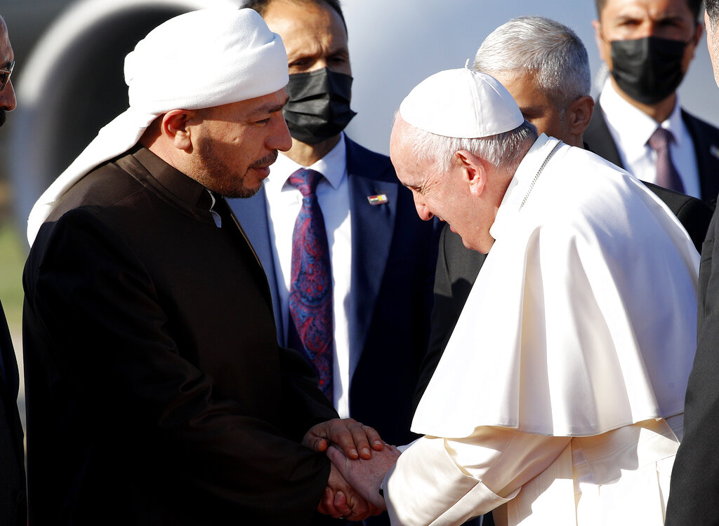 Pope Francis, right, is welcomed by Muslim clerics as he arrives at the Irbil international airport, Iraq, Sunday, March 7, 2021. Pope Francis arrived in northern Iraq on Sunday, where he planned to pray in the ruins of churches damaged or destroyed by Islamic State extremists and celebrate an open-air Mass on the last day of the first-ever papal visit to the country. (AP Photo/Hadi Mizban)