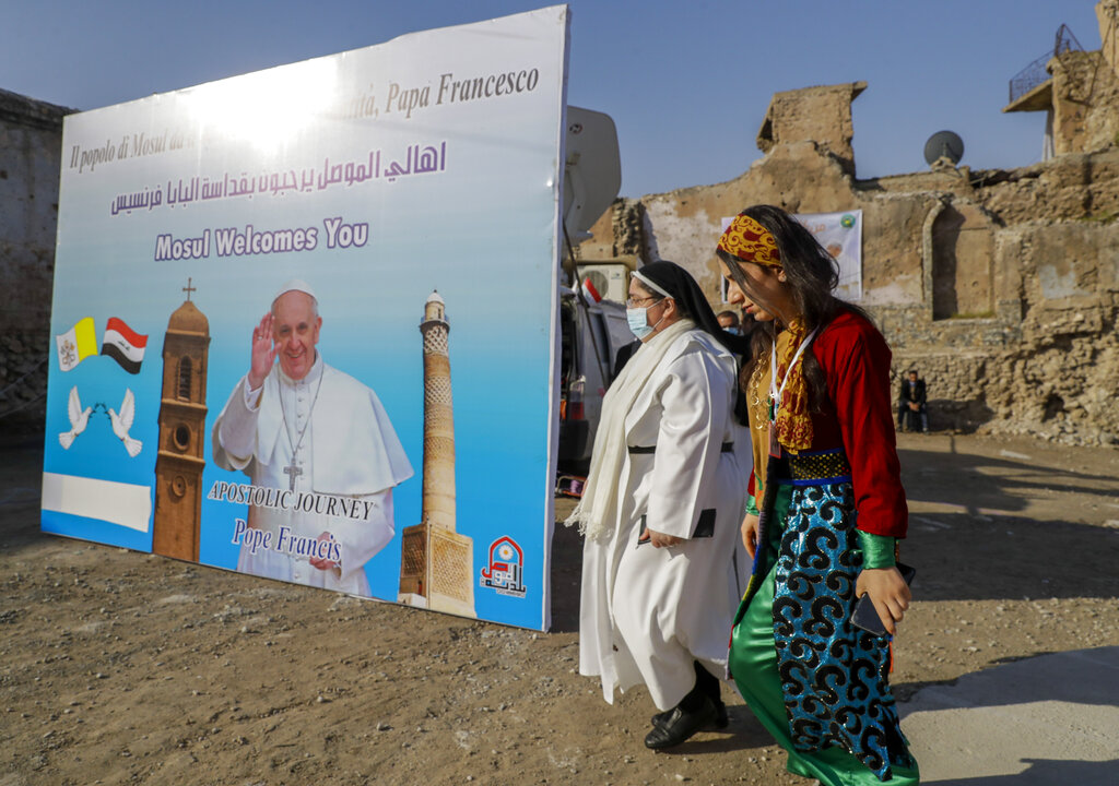 Surrounded by destroyed buildings people arrive to join Pope Francis who will pray for the victims of war at Hosh al-Bieaa Church Square, in Mosul, Iraq, once the de-facto capital of IS, Sunday, March 7, 2021. The long 2014-2017 war to drive IS out left ransacked homes and charred or pulverized buildings around the north of Iraq, all sites Francis visited on Sunday. (AP Photo/Andrew Medichini)