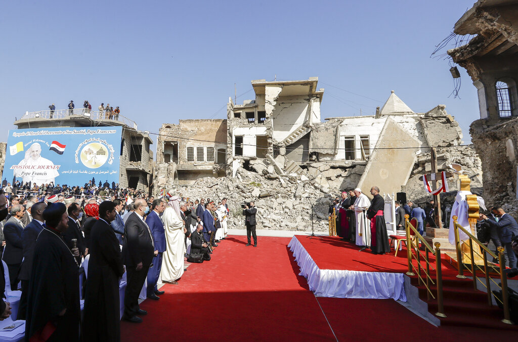 Pope Francis, surrounded by shells of destroyed churches, attends a prayer for the victims of war at Hosh al-Bieaa Church Square, in Mosul, Iraq, once the de-facto capital of IS, Sunday, March 7, 2021. The long 2014-2017 war to drive IS out left ransacked homes and charred or pulverized buildings around the north of Iraq, all sites Francis visited on Sunday. (AP Photo/Andrew Medichini)