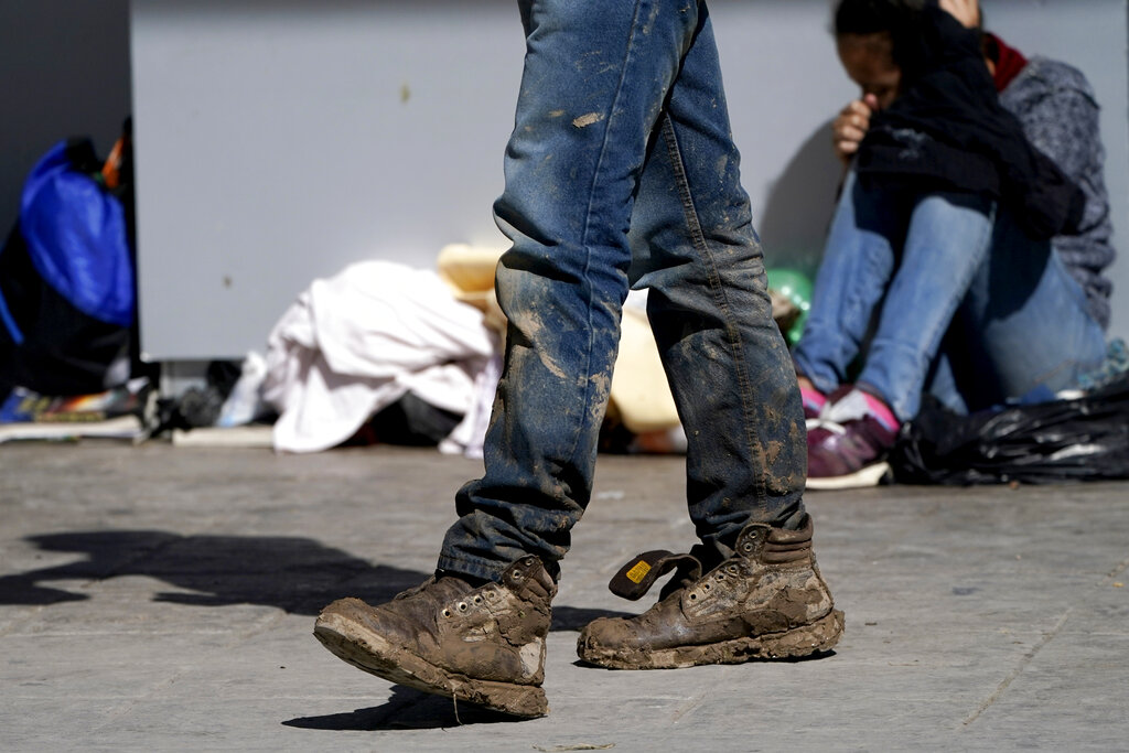 A migrant's muddy shoes are seen without laces as he walks off the customs checkpoint in Reynosa, Mexico, after being deported by U.S. Customs and Border Protection agents, Thursday, March 18, 2021. Migrants are forced to give up their shoelaces as a security measure after being taken into custody. A surge of migrants on the Southwest border has the Biden administration on the defensive. The head of Homeland Security acknowledged the severity of the problem Tuesday but insisted it's under control and said he won't revive a Trump-era practice of immediately expelling teens and children. (AP Photo/Julio Cortez)