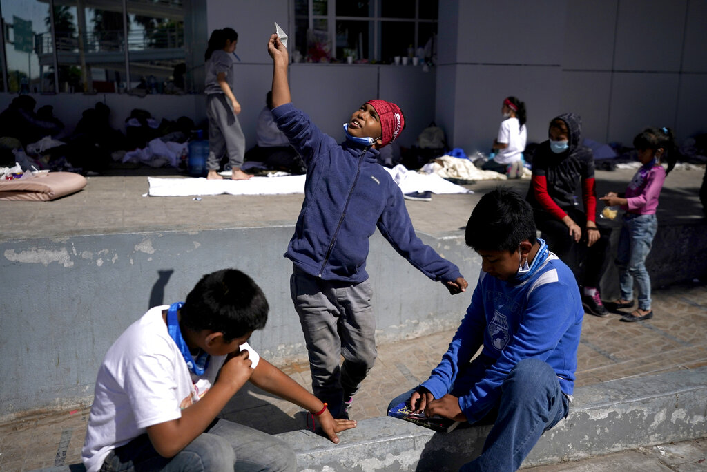 A migrant boy, center, launches a paper airplane while playing with other migrant kids at a plaza near the McAllen-Hidalgo International Bridge point of entry into the U.S., after being caught trying to sneak into the U.S. and deported, Thursday, March 18, 2021, in Reynosa, Mexico. A surge of migrants on the Southwest border has the Biden administration on the defensive. The head of Homeland Security acknowledged the severity of the problem Tuesday but insisted it's under control and said he won't revive a Trump-era practice of immediately expelling teens and children. (AP Photo/Julio Cortez)
