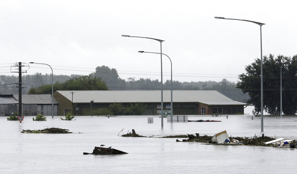 Debris floats past a partially submerged business flooded by water from the Hawkesbury River in Windsor, northwest of Sydney, New South Wales, Australia, Monday, March 22, 2021. Hundreds of people have been rescued from floodwaters that have isolated dozens of towns in Australia's most populous state New South Wales and forced thousands to evacuate their homes as record rain continues. (AP Photo/Rick Rycroft)