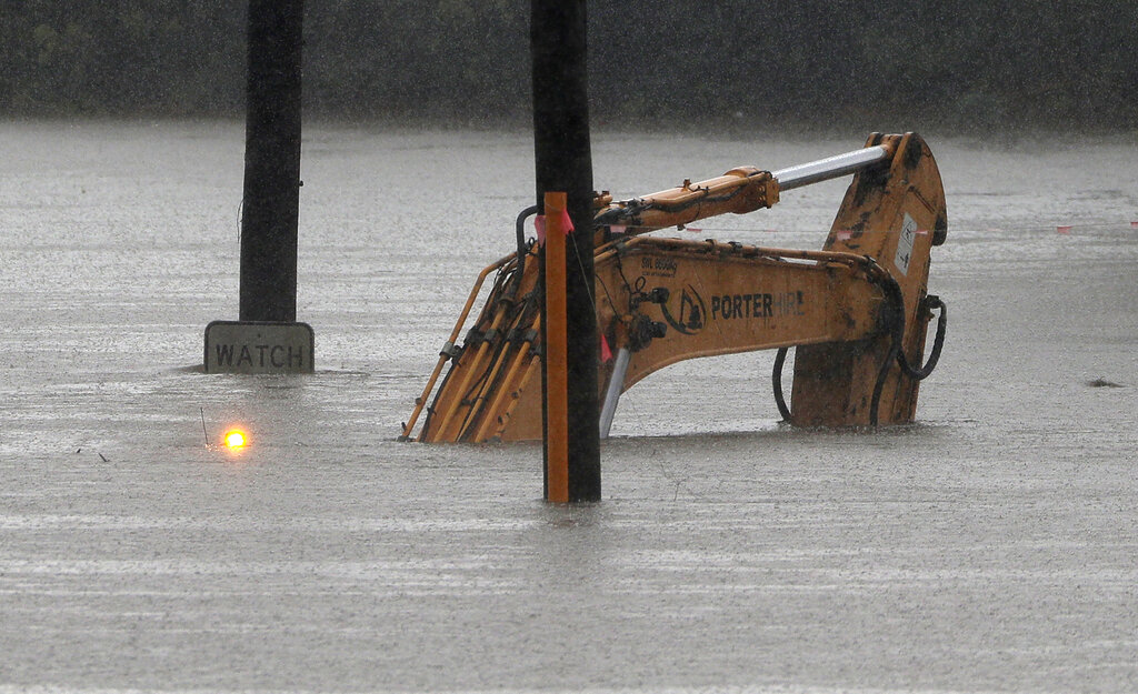 An abandoned excavator still has its flashing warning light working as it is engulfed by water from the flooded Hawkesbury River in Windsor, northwest of Sydney, New South Wales, Australia, Monday, March 22, 2021. Hundreds of people have been rescued from floodwaters that have isolated dozens of towns in Australia's most populous state New South Wales and forced thousands to evacuate their homes as record rain continues. (AP Photo/Rick Rycroft)