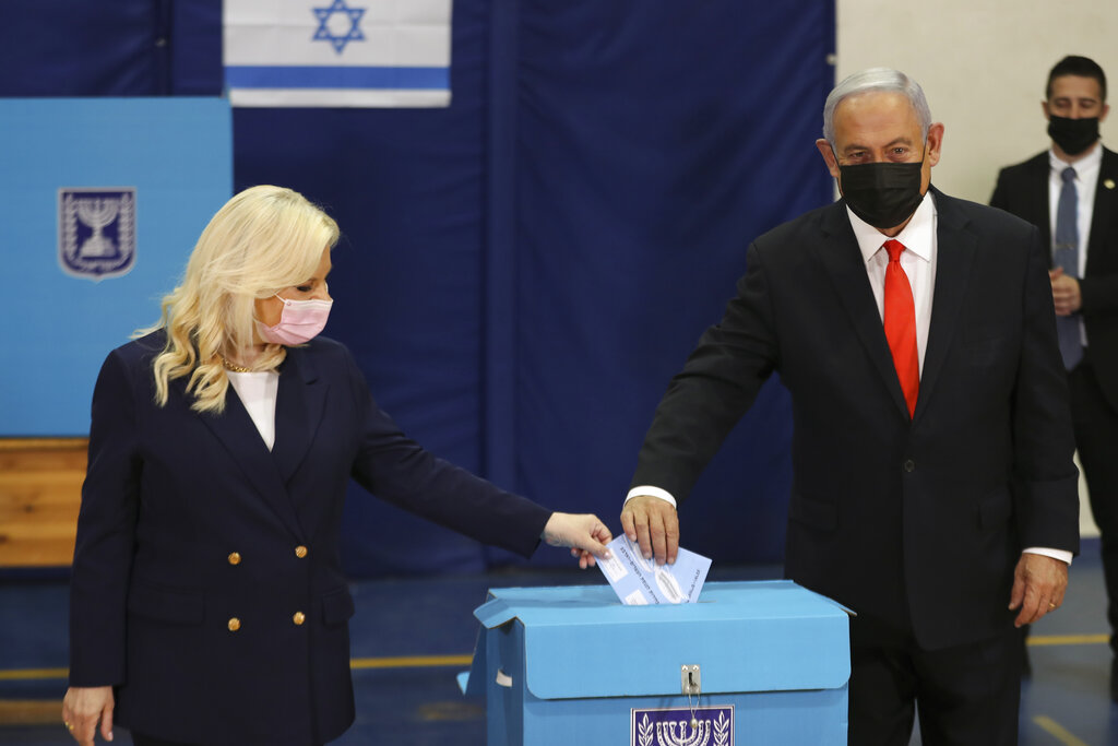 Israeli Prime Minister Benjamin Netanyahu and his wife Sara cast their ballots at a polling station in Jerusalem, Tuesday, March 23, 2021. Israelis began voting on Tuesday in the country's fourth parliamentary election in two years — a highly charged referendum on the divisive rule of  Netanyahu. (Ronen Zvulun/Pool via AP)