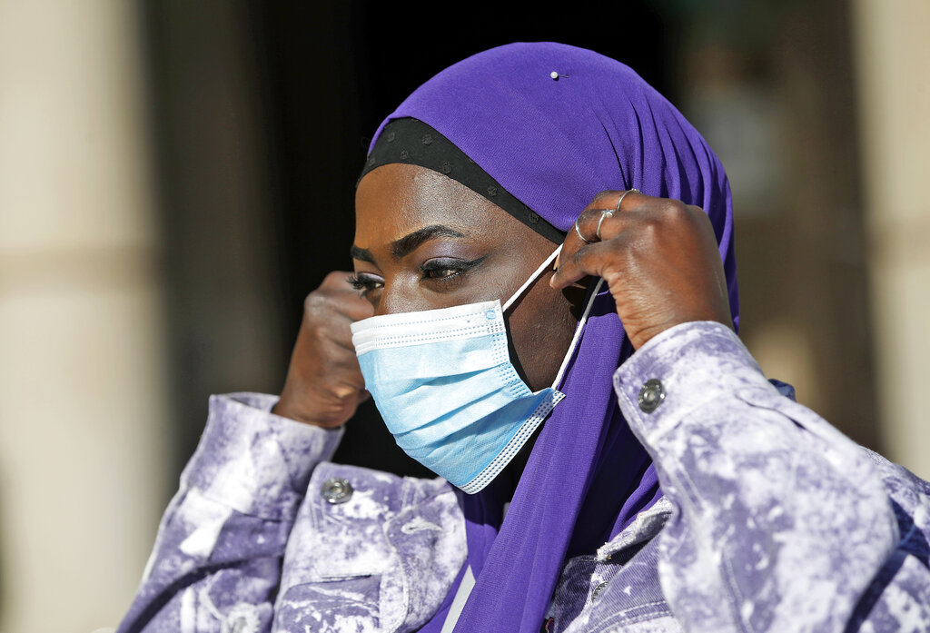 Influencer Aida Diouf Mbengue wears a sanitary mask to curb the spread of COVID-19 in front of the Duomo gothic cathedral in Milan, Italy, Tuesday, March 16, 2021. Mbengue, 19, from Senegal, is making a name for herself as a self-billed Afro-Influencer, one of a group of young people in Italy of African origin who have come together to try to increase their influence in social media. (AP Photo/Antonio Calanni)
