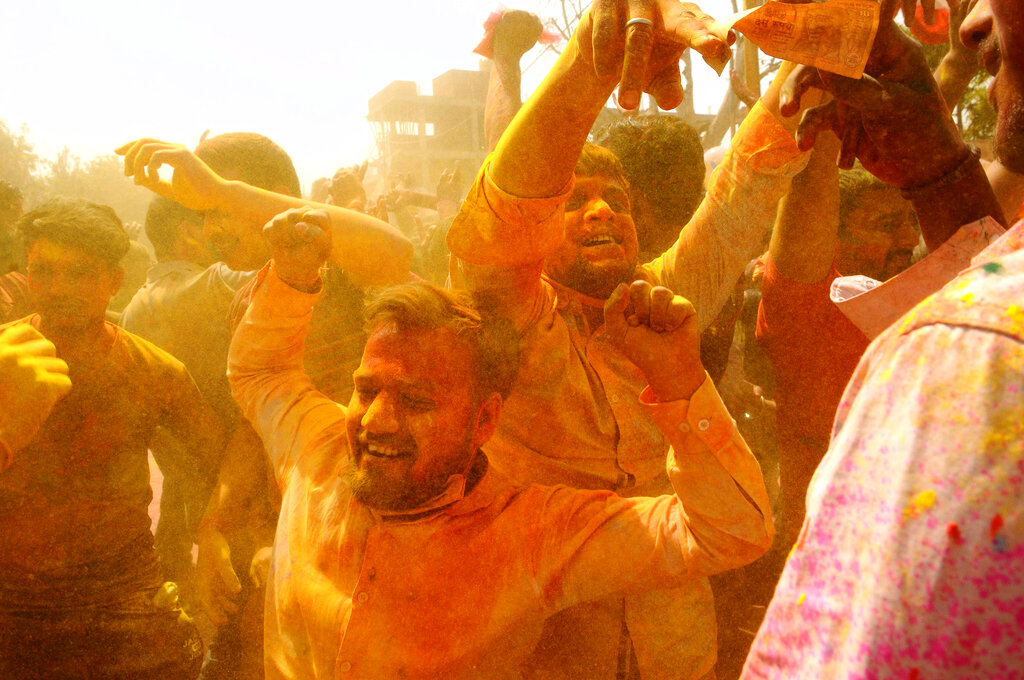 Hindu devotees dance as colored powder is thrown on them at Ladali, or Radha temple, at the legendary hometown of Radha, consort of Hindu God Krishna, during Lathmar holi, in Barsana, 115 kilometers (71 miles) from New Delhi, India, Tuesday, March 23, 2021. In Lathmar Holi the women of Barsana beat men from Nandgaon, the hometown of Krishna, with wooden sticks in response to their teasing. (AP Photo)