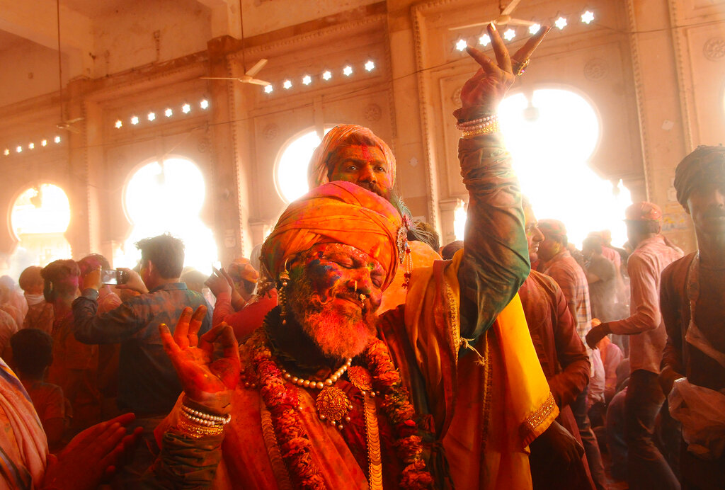 Hindu devotees dance as colored powder is thrown at them at Ladali, or Radha temple, at the legendary hometown of Radha, consort of Hindu God Krishna, during Lathmar Holi, in Barsana, India, 115 kilometers (71 miles) from New Delhi, on Tuesday, March 23, 2021. During the holiday, the women of Barsana beat men from Nandgaon, the hometown of Krishna, with wooden sticks in response to their teasing. (AP Photo)