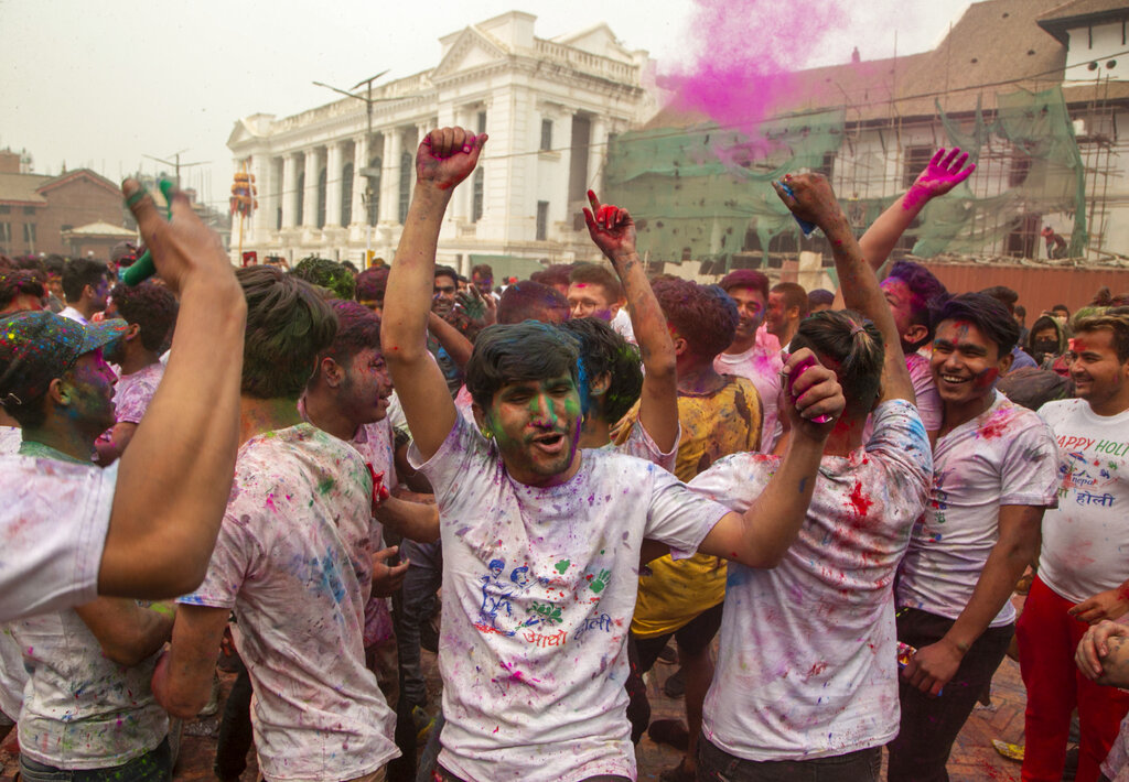 Nepalese people throw colors on each other as they celebrate Holi festival in Kathmandu, Nepal, Sunday, March 28, 2021. Despite authorities urging people to celebrate the festival indoors only in view of COVID-19, thousands were celebrating outdoors in the capital. (AP Photo/Niranjan Shrestha)