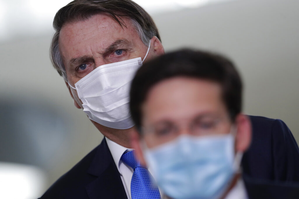 Brazilian President Jair Bolsonaro attends a press conference to announce the start of emergency aid for the COVID-19 pandemic at Planalto presidential palace in Brasilia, Brazil, Wednesday, March 31, 2021. In front is the Minister of Citizenship Joao Roma. (AP Photo/Eraldo Peres)