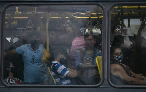 Commuters wearing masks due to the COVID-19 pandemic crowd a public Rapid Transit Bus (BRT) in Rio de Janeiro, Brazil, Tuesday, March 30, 2021. (AP Photo/Bruna Prado)