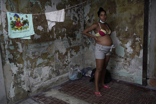 Actress Kelly Regina da Silva, who before the pandemic hit had made it out of her working-class slum, poses for a photo in the building where she now lives in a small room in one of the city center's squats, in Rio de Janeiro, Brazil, Tuesday, March 16, 2021. Even among the world's richest nations, a PricewaterhouseCoopers survey this month found COVID-19 threatened to reverse the important gains women made over the last decade with 