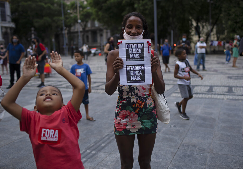A woman holds a sign with a message that reads in Portuguese: 