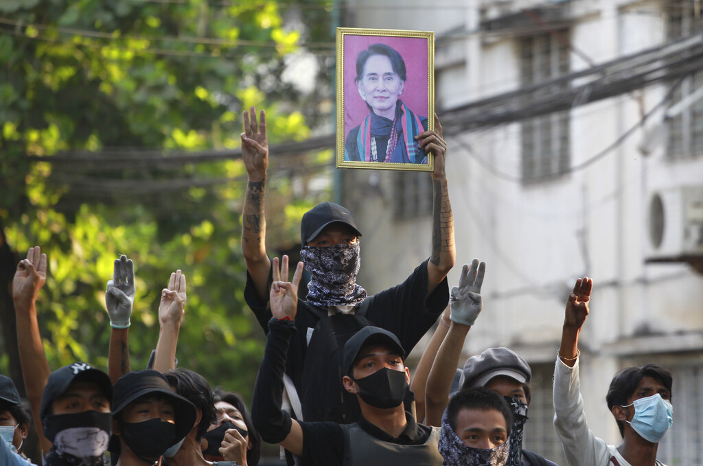 Anti-coup demonstrators raise the three finger of resistance and a portrait of deposed leader Aung San Suu Kyi as prepare to confront police during a protest in Tarmwe township, Yangon, Myanmar, Thursday, April 1, 2021. (AP Photo)