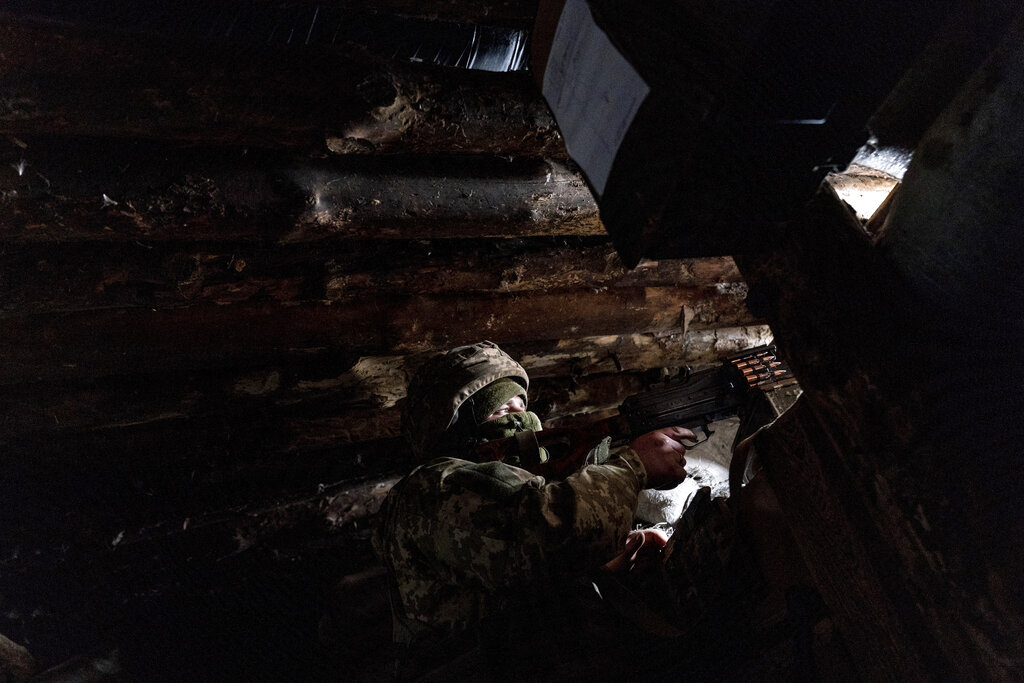 FILE - In this Friday, March 5, 2021 file photo, a Ukrainian serviceman on guard with a machine gun in his shelter near the front-line town of Krasnohorivka, eastern Ukraine. Ukraine’s military said Tuesday, April 6, 2021 that two of its soldiers were killed within 24 hours in the country’s east, where Ukrainian forces have been fighting Russian-backed separatists since 2014. The Joint Forces Operation reported Tuesday that the two servicemen sustained fatal gunshot wounds as a result of a “hostile fire.” Firefights have occurred sporadically since tensions in eastern Ukraine escalated in late February. (AP Photo/Evgeniy Maloletka, File)