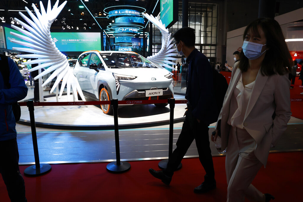 Attendees pass by a vehicle from the GAC Group displayed during the Shanghai Auto Show in Shanghai on Monday, April 19, 2021. Automakers are looking to China, their biggest market by sales volume and the first major economy to rebound from the pandemic, to revive sales and reverse multibillion-dollar losses. (AP Photo/Ng Han Guan)