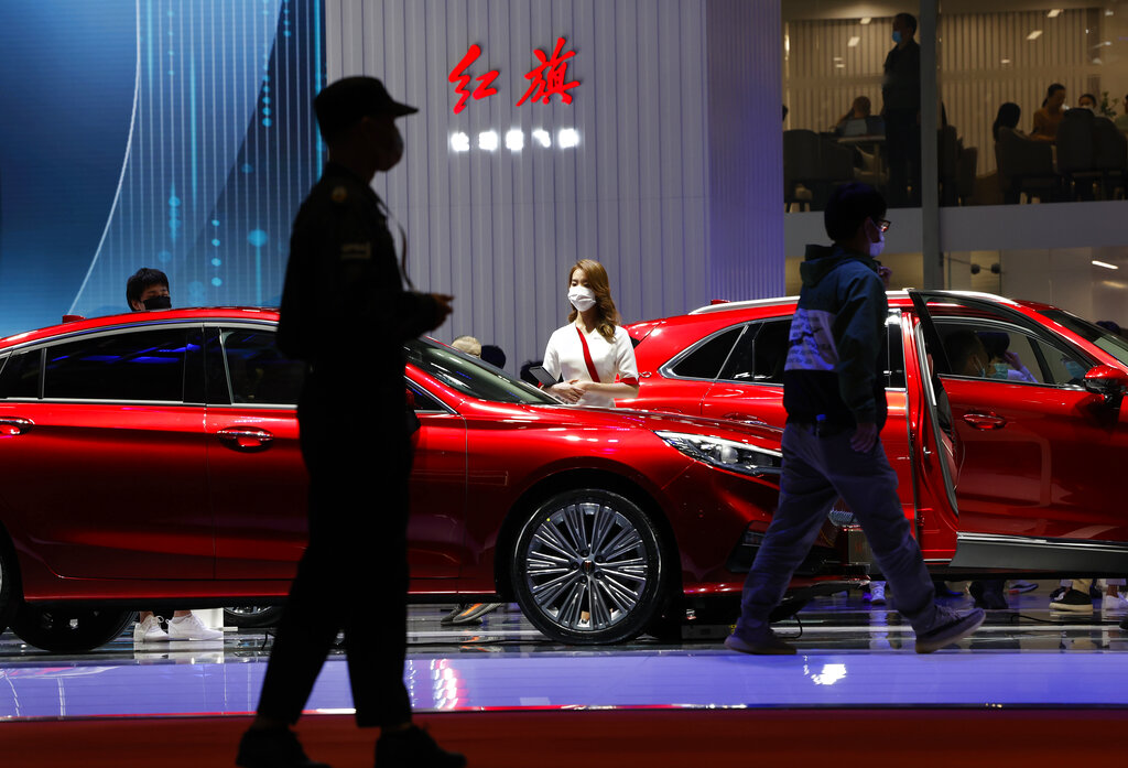 A promoter for Chinese luxury auto brand Hongqi waits for visitors near the brand's latest cars at the Shanghai Auto Show in Shanghai on Tuesday, April 20, 2021. Automakers are looking to China, the biggest auto market by sales volume and the first major economy to rebound from the pandemic, to propel a revival in demand and reverse multibillion-dollar losses. (AP Photo/Ng Han Guan)