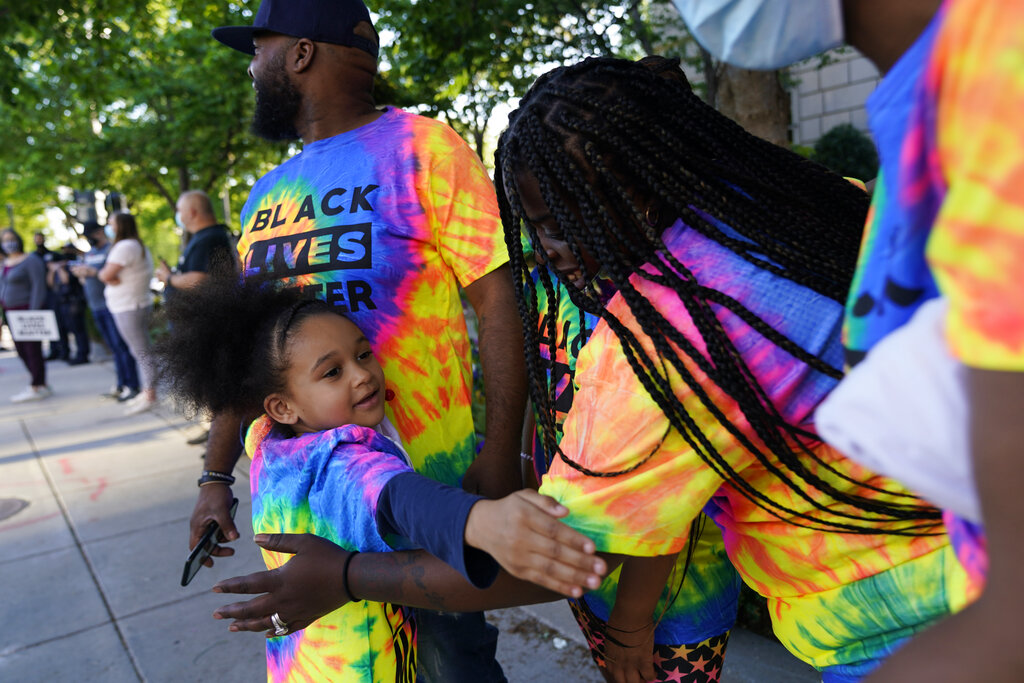 Mahkhyieah Lee, 5, of Scranton Pa., hugs her mom Erin Lee as they visit Black Lives Matter Plaza with other family members near the White House on Tuesday, April 20, 2021, in Washington, after the verdict in Minneapolis, in the murder trial against former Minneapolis police officer Derek Chauvin was announced. (AP Photo/Jacquelyn Martin)