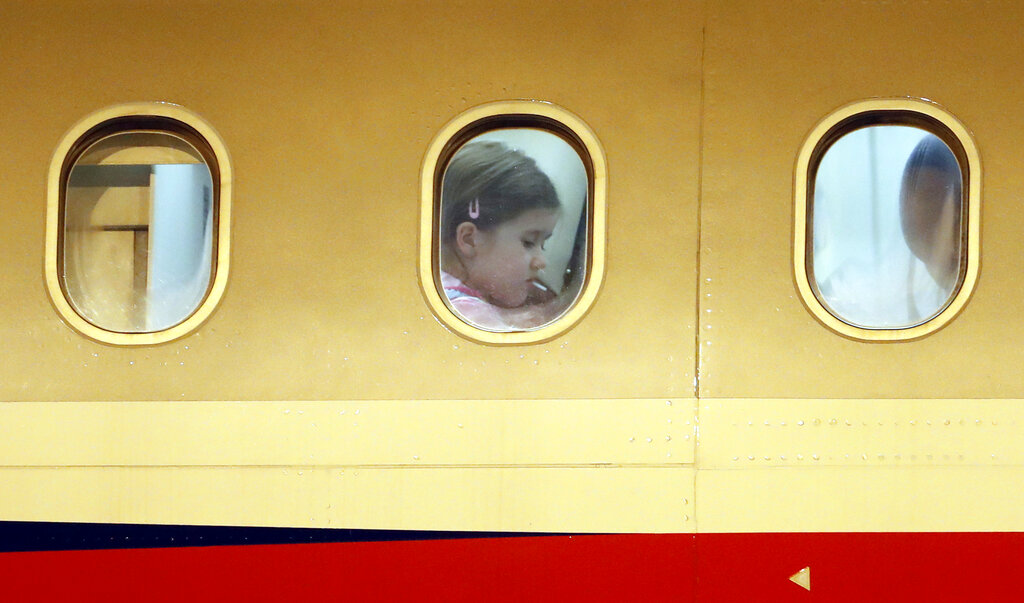 A young girl is seen in a window as Czech diplomats and their families arrive at the Vaclav Havel airport in Prague, Czech Republic, Monday, April 19, 2021. Russia has ordered 20 Czech diplomats to leave the country within a day in response to Prague's expulsion of 18 Russian diplomats. The Czech government has alleged the Russian Embassy staffers were spies for a military intelligence agency that was involved in a fatal ammunition depot explosion in 2014. (AP Photo/Petr David Josek)