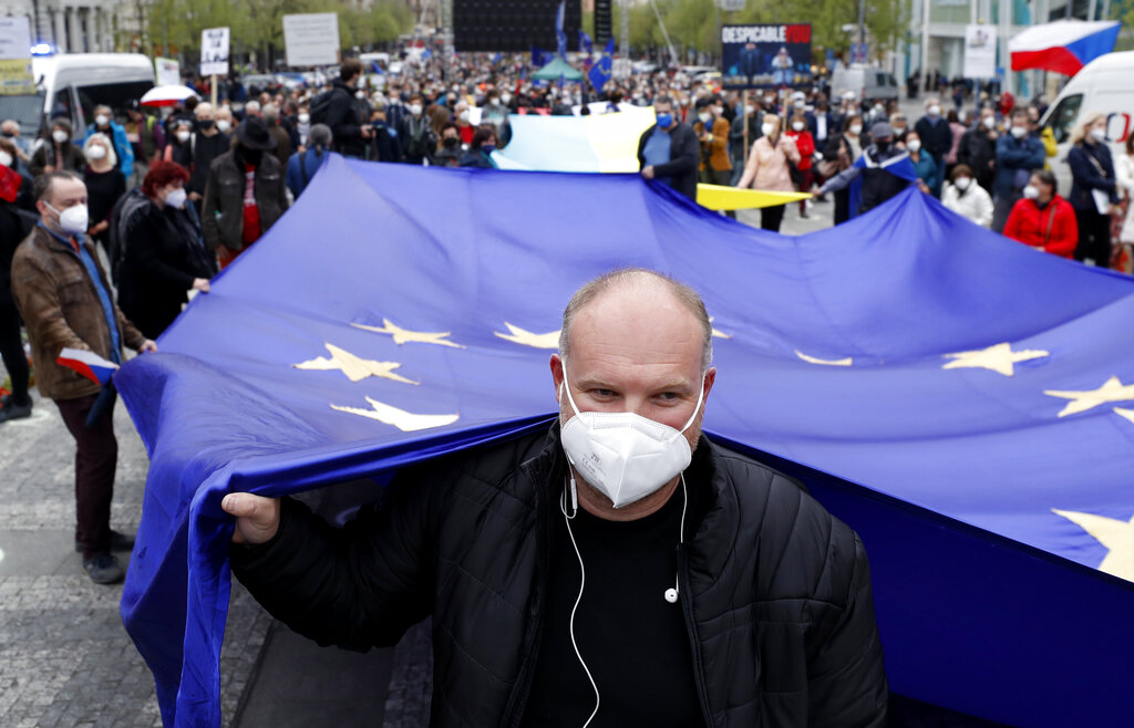 Man holds an EU flag during a demonstration in Prague, Czech Republic, Thursday, April 29, 2021. Thousands of Czechs have rallied in the capital against President Milos Zeman, accusing him of treason for his pro-Russian stance over the alleged participance of Russian spies in a Czech huge ammunition explosion. (AP Photo/Petr David Josek)
