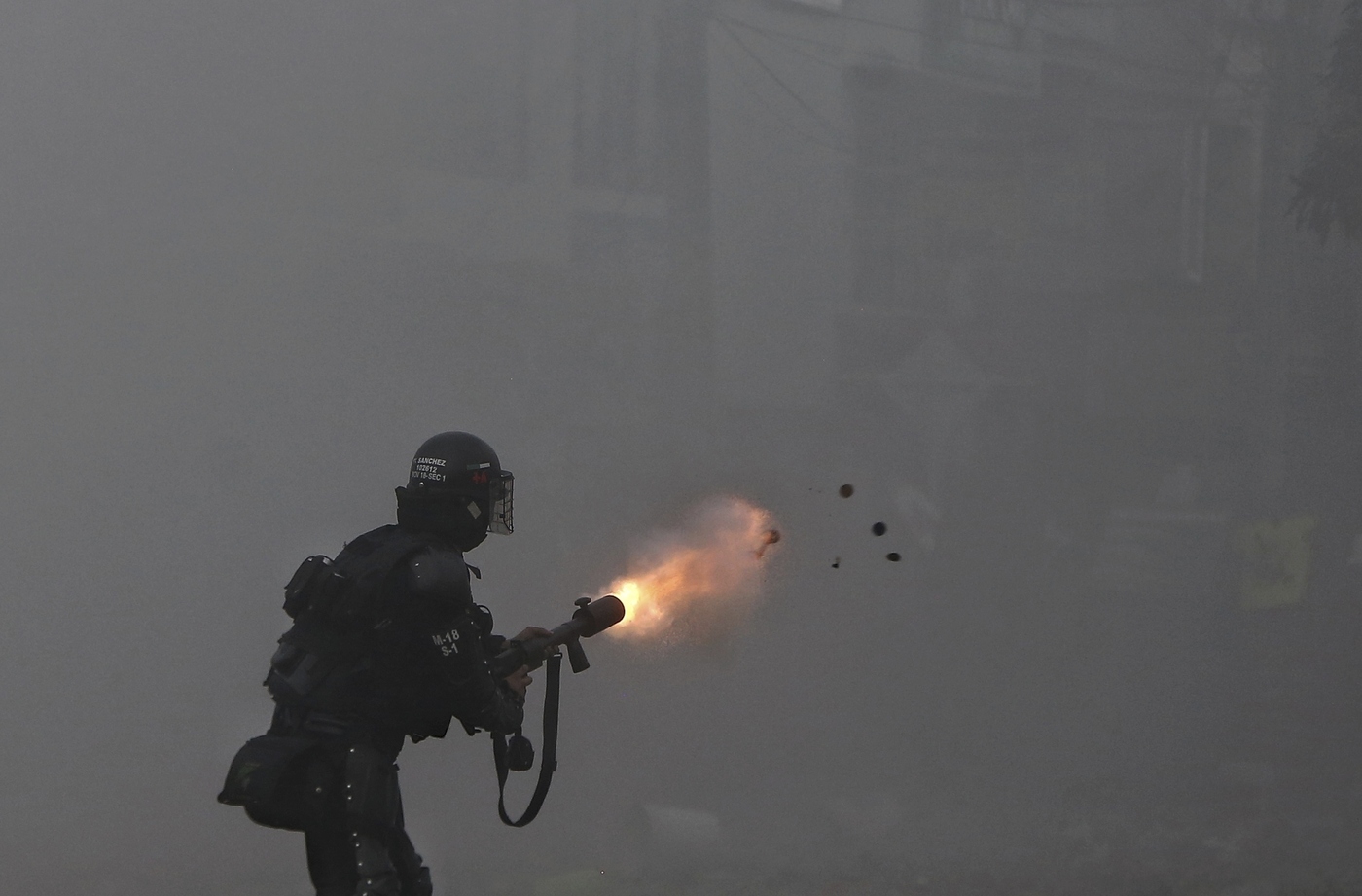 A police officer fires tear gas at protesters during a strike against tax reform in Cali, Colombia, Monday, May 3, 2021. Colombia's President Ivan Duque withdrew the government-proposed tax reform on Sunday. (AP Photo/Andres Gonzalez)