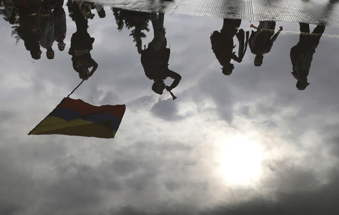 University student are reflected on a puddle during a national strike against tax reform in Bogota, Colombia, Monday, May 3, 2021. Colombia's President Ivan Duque withdrew the government-proposed tax reform on Sunday. (AP Photo/Fernando Vergara)