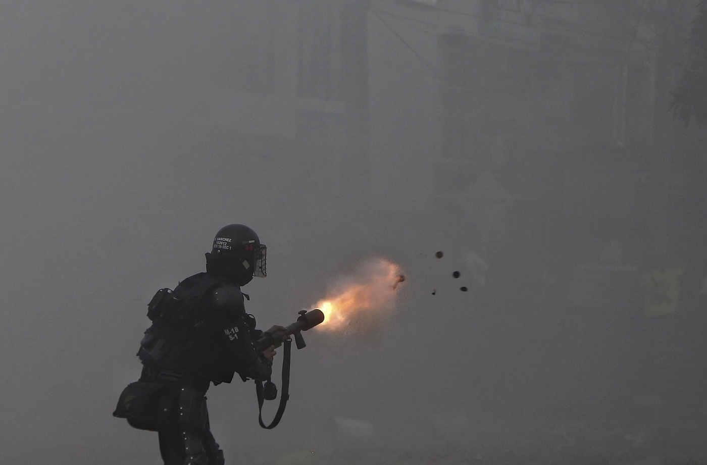 A police officer fires tear gas at protesters during a national strike against tax reform in Cali, Colombia, Monday, May 3, 2021. Colombia's President Ivan Duque withdrew the government-proposed tax reform on Sunday. (AP Photo/Andres Gonzalez)